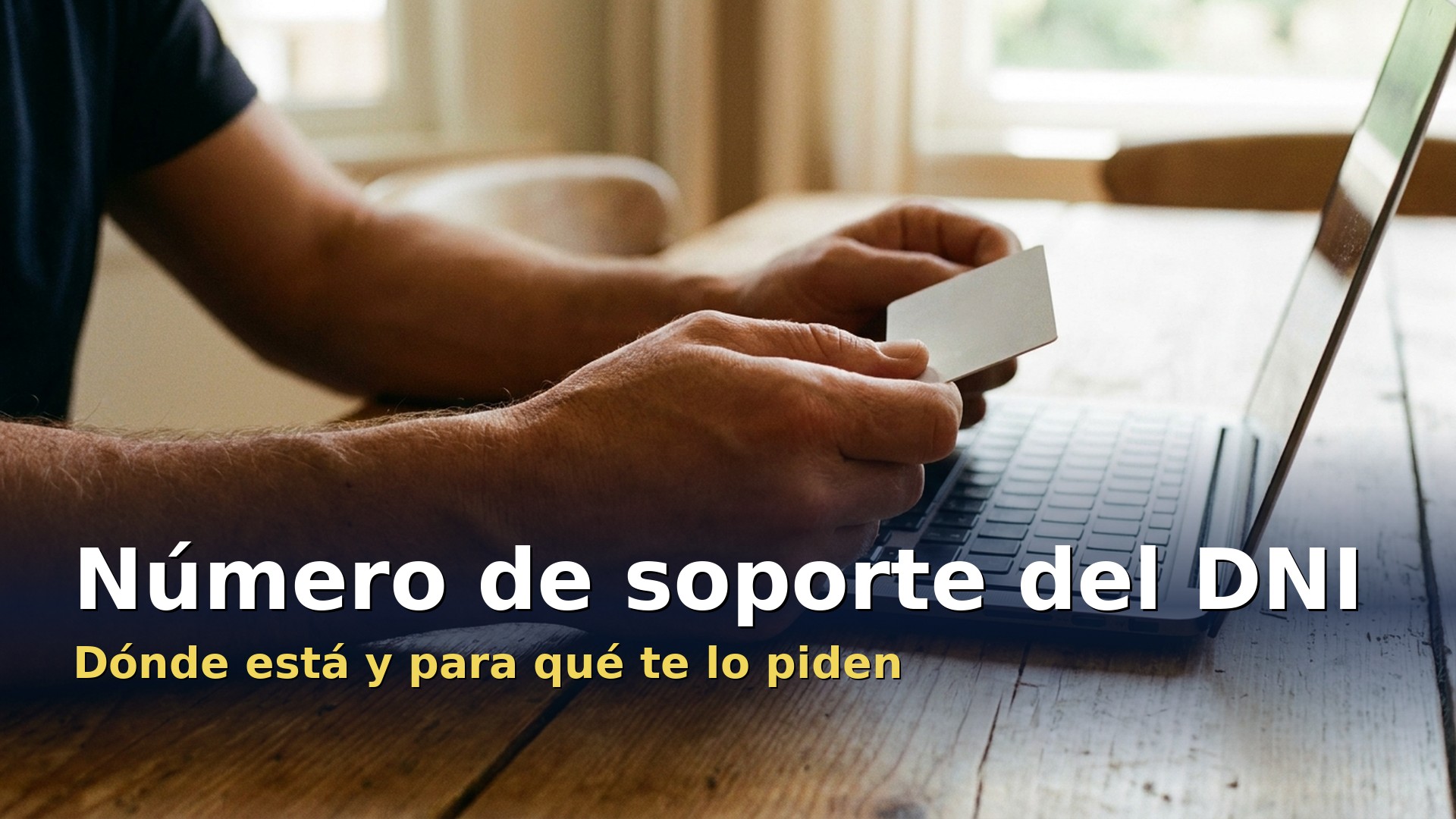 Manos sosteniendo el DNI junto a un portátil para buscar el número de soporte