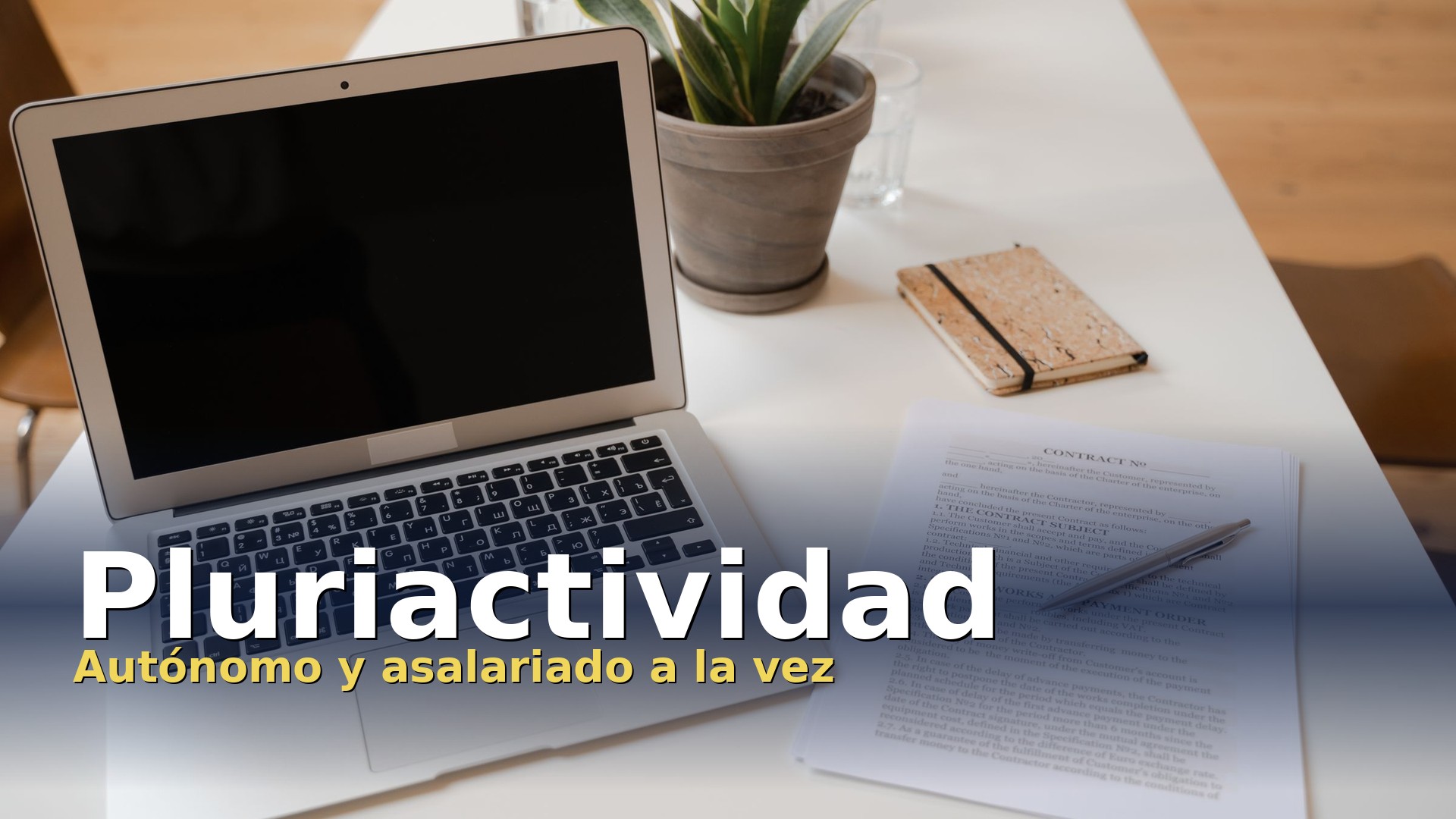 Pluriactividad: portátil y contrato sobre una mesa de trabajo